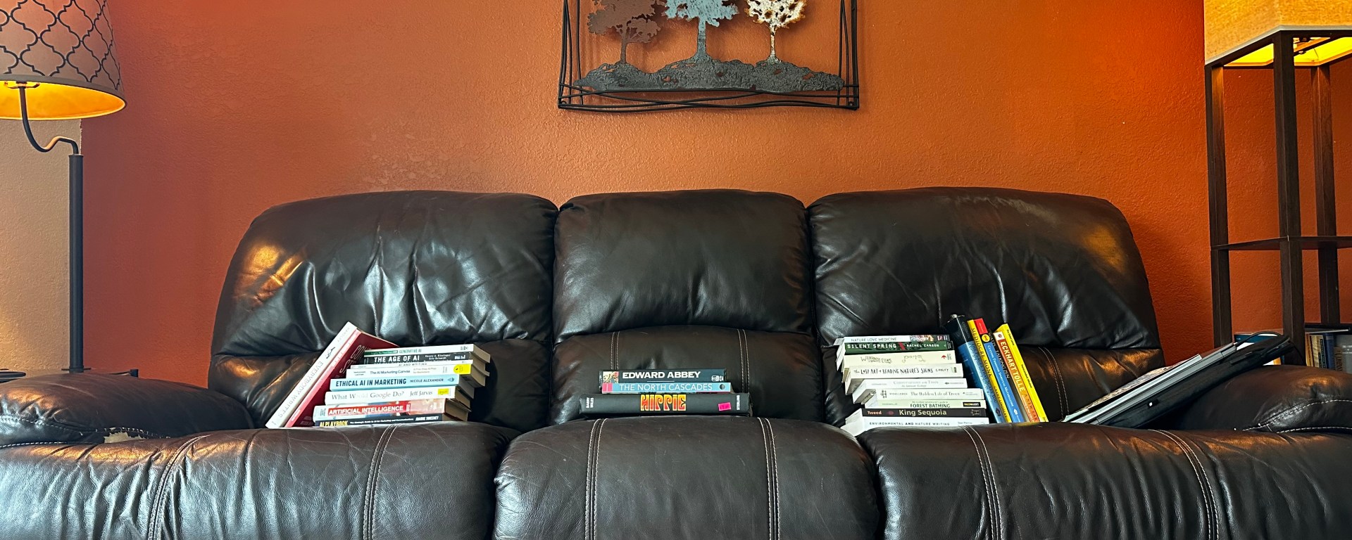 a couch with piles of books about AI and trees